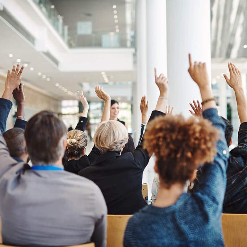 People raising hands in meeting